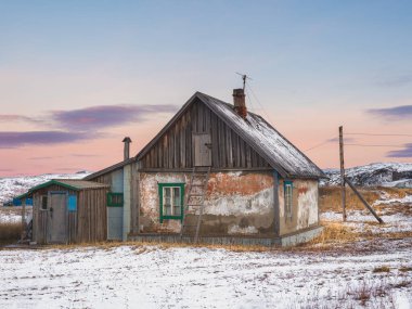 Tavan arasına merdiven dayamış eski bir ev. Otantik bir Rus köyü, sert Kuzey Kutbu doğası. Teriberka.
