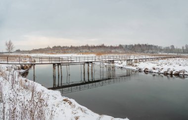 Kış nehri üzerinde eski bir yaya köprüsü. Rusya.