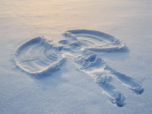 Snow angel made in the white snow in the evening. Top flat overhead view.