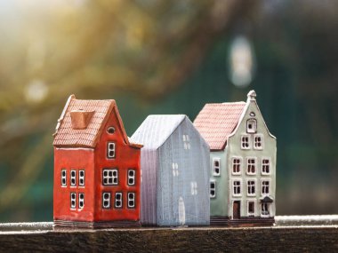 Güneşli bir arka planda üç oyuncak ev. Emlak, inşaat, kiralık konut kavramı.