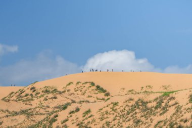 Büyük bir kum tepesinde küçük turist siluetleri. Dağıstan. Sarykum kumulu.