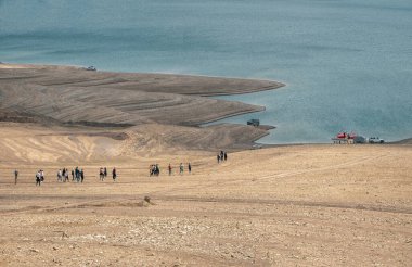 - Rusya. Dağıstan. Mayıs 2021. Bir grup turist teknelere binmeye gider. Uzak görünüm. Sulak rezervuarı, Dağıstan.