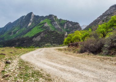 Boş toprak dağ yolu. Engebeli yeşil dağlara giden toprak yol..
