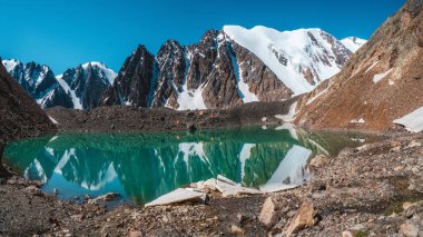 Sahilde çadırları olan Altai 'deki Mavi Dağ Gölü' nün panoramik manzarası. Güzel turkuaz göl. Sonbahar zamanında alışılmadık saydam göl.