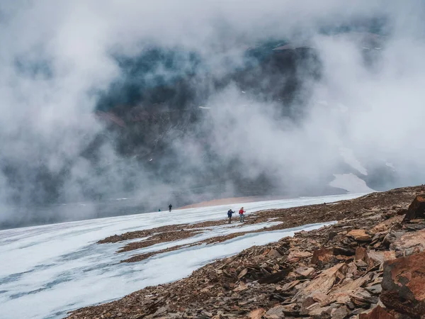 Soft focus. Tourists come to top of misty snowy hill. teamwork and victory, teamwork of people in difficult conditions. Difficult climb to the top of the mountain.