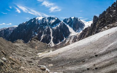 Yüksek karlı dağların arka planında bir vadi olan görkemli buzul dağı vadisi. Dağların yükseklerinde, kar ve buzla kaplı buzulun panoramik manzarası. Altai kış manzarası.
