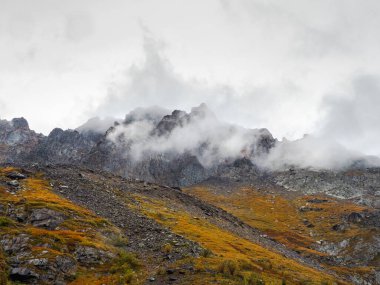 Yumuşak odaklanma. Beyaz bulut karanlık dağ zirvelerine indi. Sabah dağlarında ışık. Parlak sonbahar, yüksek dağ arkaplanı..