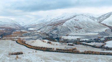 Soğuk ve karlı dağ panoramik manzarası. Dağ nehri Argut 'la muhteşem dağlık arazi alçak bulutların altındaki sisli dağların arka planında kış renklerinde.. 