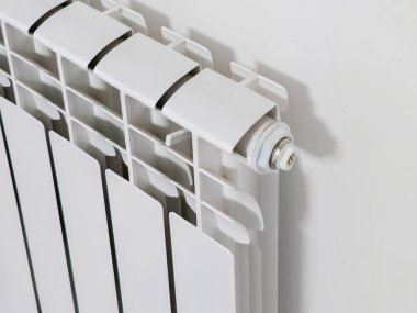 Üzerinde beyaz bir boru olan beyaz bir radyatör. Radyatör duvarda. Tamir işleri. Eve, yaşam alanları için yeni bir çelik radyatörü olan merkezi bir ısıtma sistemi kuruluyor..