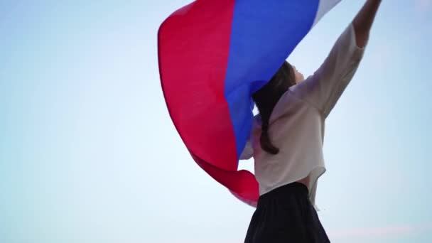 Podekscytowana kobieta wiruje flagą narodową przeciwko niebu. Patriotyzm i niezależność — Wideo stockowe