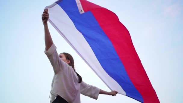 Persona con la bandera de Rusia se levanta y se lava en la distancia. Una mujer patriota mira felizmente al futuro — Vídeo de stock