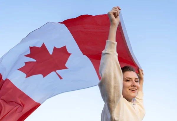 Bir kadın elinde Kanada bayrağını taşıyor, rüzgarda sallanıyor. Ulusal sembolü olan özgür bir ülkede göçmen.
