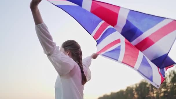 Una persona británica lleva la bandera nacional en sus manos. El símbolo de Gran Bretaña saludando al viento — Vídeo de stock