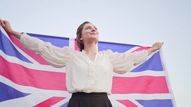 Patriota con la bandera nacional de Gran Bretaña. Mujer independiente sonríe y se regocija — Vídeo de stock