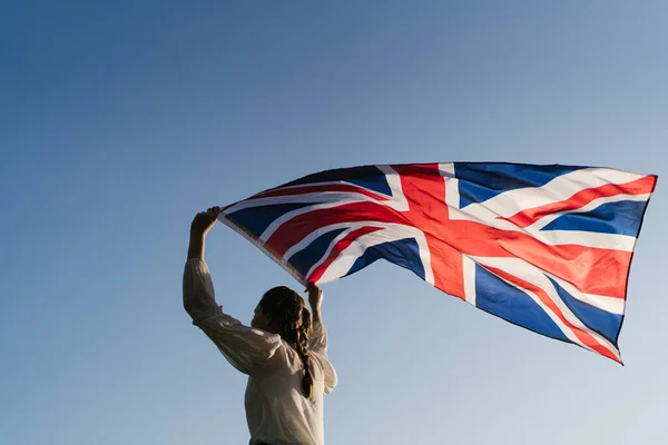女性は澄んだ空に対して英国の旗で走ります。イギリス市民の愛国心 — ストック写真