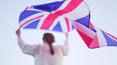 İngiliz bayrağı yavaş çekimde bir kadının arkasında güzel bir şekilde gelişir.