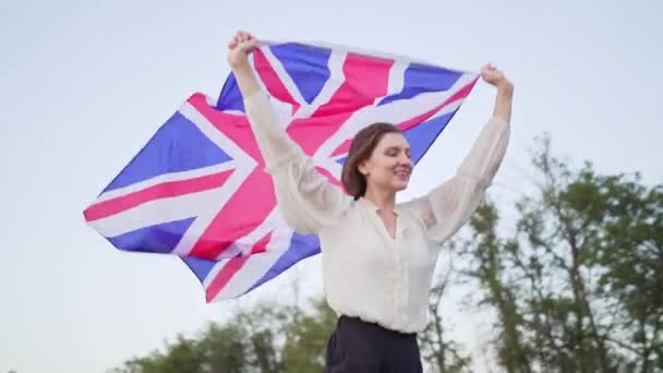 Håper å komme seg ut av sikkerhetssonen. Britisk ung kvinnelig student med nasjonalt flagg – stockvideo
