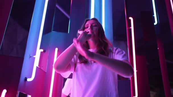 Eine Frau genießt das Nachtleben auf der Party und tanzt wunderschön neben farbigen Neonlampen — Stockvideo