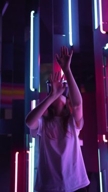 Dikey video - kafasında sanal gerçeklikteki şeylere dokunan VR cihazlı modern bir kadın. Yeni eğlence deneyimi - gelecekteki uzay simülasyonu