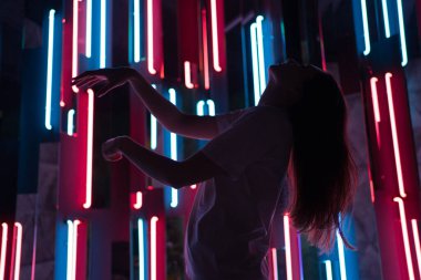 İnce kadın neon arka planda rahatça dans ediyor. Dansçının silüeti farklı renklerde güzel bir ışıkta