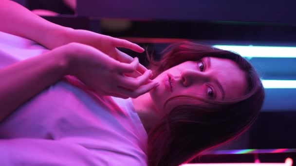 Vídeo vertical - una señora en una hermosa luz posando para la cámara. Lámparas azules y rosas en el fondo — Vídeos de Stock