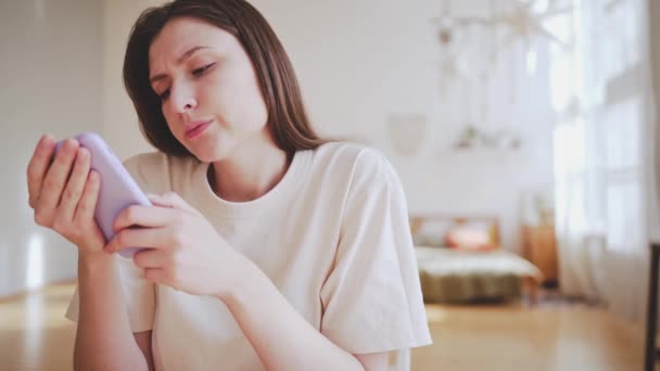 Ideges fiatal nő egy telefonnal egy hangulatos belső térben. Információtúlterhelés — Stock videók