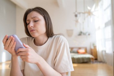 Rahat bir iç mekanda telefonu olan gergin genç bir kadın. Fazla bilgi yüklenmesi