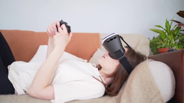 Παίζοντας εικονική πραγματικότητα ξαπλωμένος στον καναπέ. Σύγχρονο σκανδιναβικό εσωτερικό. Νέα εμπειρία — Αρχείο Βίντεο