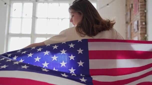 4k 10 bit. De Amerikaanse vlag wappert prachtig achter een vrouw die het licht in loopt. 4 juli in de Verenigde Staten — Stockvideo