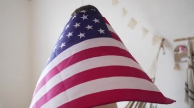 4k 10 bit. Amerikan bayrağı. Gururlu bir kadın ulusal bayrağın önünde duruyor ve uzaklara bakıyor. Özgürlük, demokrasi ve bağımsızlık
