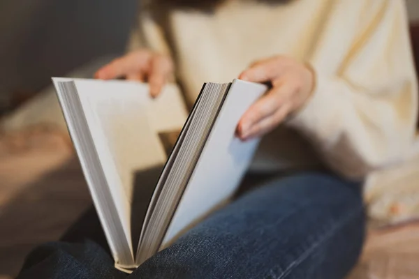 Een jonge vrouw opent het boek. Leerinformatie. Wit groot boek op voeten close-up — Stockfoto