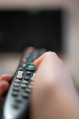 Televizyonun uzaktan kumandalı düğmeleri. Kanepede eğlence. TV programları değiştiriliyor