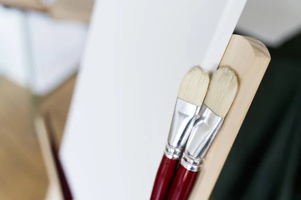 Escova para desenho e tela branca no cavalete close-up — Fotografia de Stock