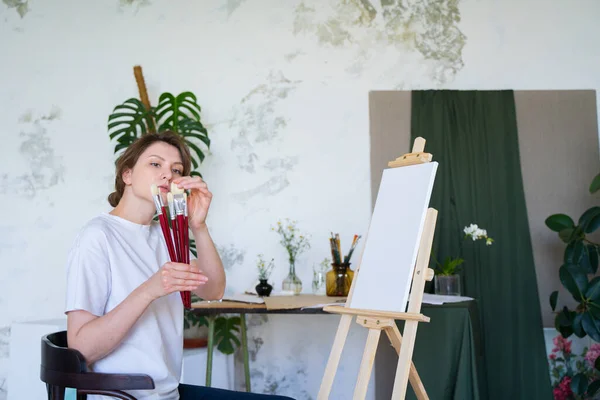 Egy női művész megnézi az ecseteket rajzoláshoz. Tehetséges festő. Szakmai kreatív oktatás — Stock Fotó