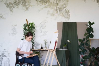 Ressam paletteki boyaları sıkar. Yetenekli sanatçı stüdyosunda çalışıyor.