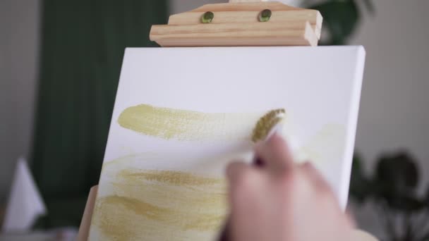 Pintura al óleo. El artista tiene la idea de dibujar. Una mujer aplica pintura amarilla a un lienzo blanco — Vídeo de stock