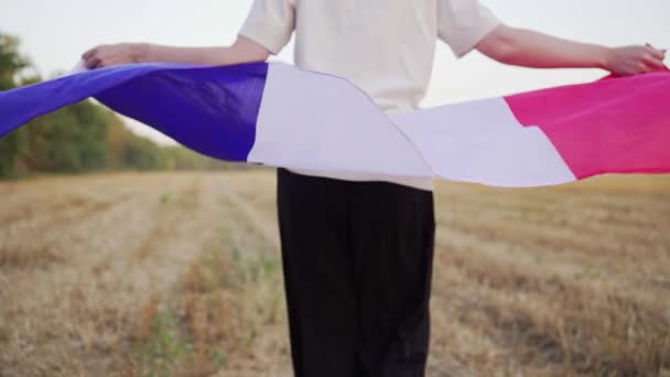 Een vrouw loopt met de vlag van Frankrijk bij zonsondergang. Patriottisme en trots — Stockvideo