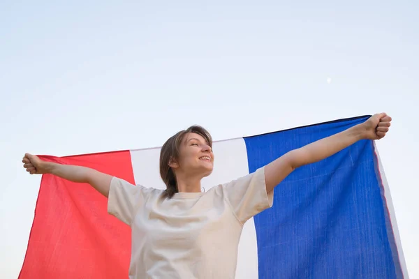 Flag of France in the wind. A woman holds the national symbol of her country — Stock Photo, Image