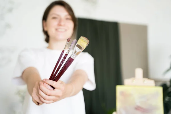 El artista muestra los pinceles a la cámara. Artista contemporánea. Joven emprendedor, retrato — Foto de Stock