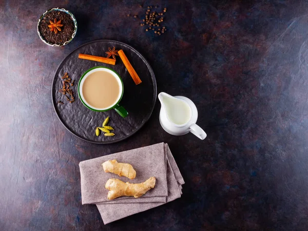 Masala çayı. Geleneksel Hint içeceği - siyah tabakta çeşitli baharatlar bulunan Masala çayı. Baharatlı seramik çay ve süt sürahisi