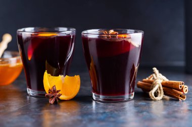 Karanlık bir arka planda sıcak şarap. İki bardak sonbahar şarabı ve malzemesi. Şarap ve ballı Noel içkisi