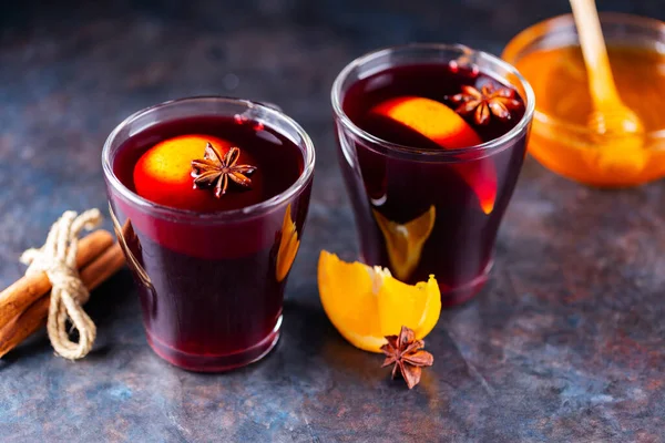 Mulled wine on a dark background. Two cups of autumn mulled wine and ingredients. Christmas hot drink with wine and honey