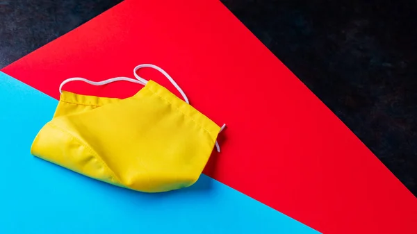 Gelbe Gesichtsmaske Auf Buntem Papier Gesichtsschutzmaske Auf Blau Rotem Hintergrund — Stockfoto