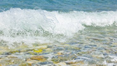 Deniz dalgası ve çakıl taşı. Yaz tatili kavramı. Kıyı şeridinde köpüklü deniz dalgası olayı. Seyahat kavramı