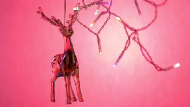 ピンクの背景にクリスタルのガラスの鹿 ホログラフィックな鹿が弦の上で揺れる ネオンライトで鹿のおもちゃ お祭り騒ぎだ 4Kビデオ — ストック動画