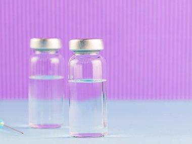 Aşı ve şırınga. Önleme ve aşılama için mor arka planda aşı ve şırınga. Aşı ve tıbbi konsept. Boşluğu kopyala