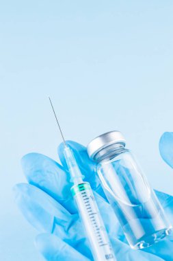 Aşı şişesi ve şırınga doktor elinde. Doktor 'un elinde ameliyat eldiveni, elinde aşı şişesi ve şırınga var. Aşılama ve aşılama