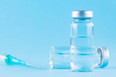 Aşı ve şırınga. Önleme ve aşılama için mavi arka planda aşı ve şırınga. Aşı ve sağlık sigortası konsepti. Boşluğu kopyala