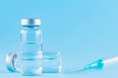 Aşı ve şırınga. Önleme ve aşılama için mavi arka planda aşı ve şırınga. Aşı ve sağlık sigortası konsepti. Boşluğu kopyala