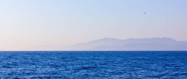 Sis ve dağlarla kaplı bir deniz manzarası. Gün batımında deniz manzarası. Denizden dağlara kadar sisli bir manzara. Dramatik sahneler ve doğanın güzelliği. Boşluğu kopyala